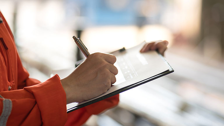 Worker writing down on clipboard